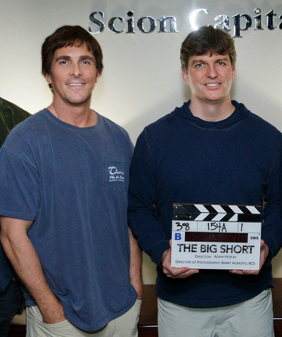Two men stand smiling in front of a "Scion Capital" sign, with one holding a film clapperboard for "THE BIG SHORT," directed by Adam McKay. The image connects to the post by featuring Michael Burry (right), the hedge fund manager whose real-life bet against the housing market inspired the film, with his quote warning investors about not truly understanding what they own.