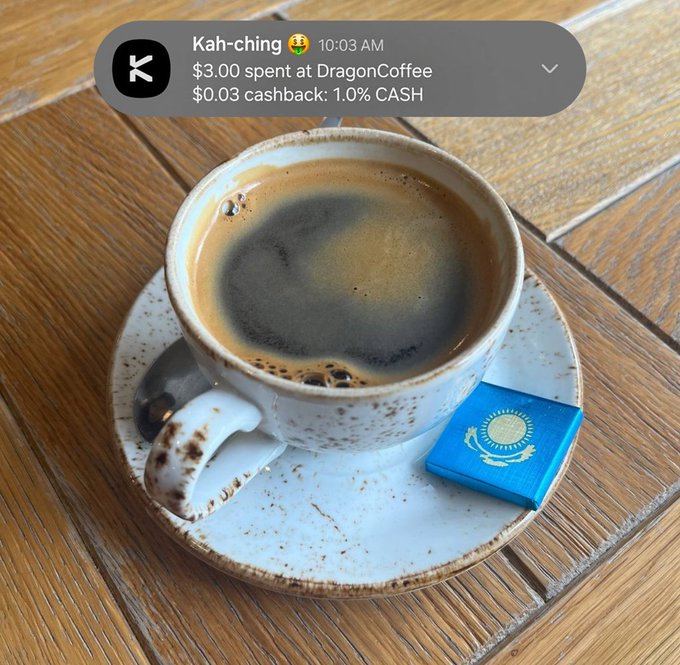 The image shows a cup of coffee sitting on top of a white saucer, placed on a wooden table. The text in the image suggests that there might be an opportunity for users to get cashback on their purchases through a mobile payment app. This implies that the user's morning started with a cup of coffee and they used a mobile payment method to pay for it.