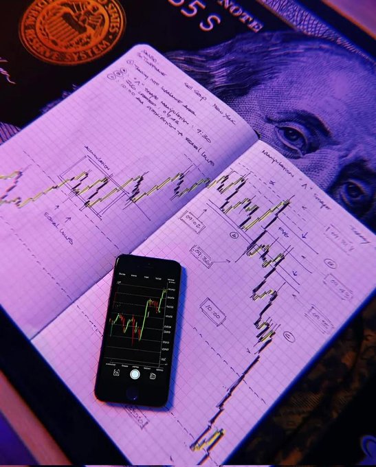 The image features an open book with a graph and a cell phone on top of it, both sitting on a table. The cell phone has the app graphs loaded onto its screen, displaying stock charts or financial information. This scene suggests that someone is studying or analyzing stock market trends using these tools.
