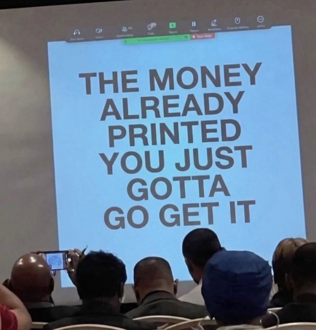 A crowd watches a presentation displaying the motivational slide "THE MONEY ALREADY PRINTED YOU JUST GOTTA GO GET IT," which ties to the post's message that owning fractions of crypto like 0.239 BTC, 7.99 ETH, or 199.1 SOL is still a worthwhile investment worth pursuing.