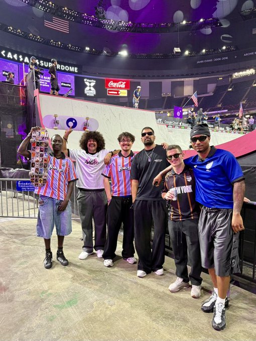 A group of seven people pose together holding up phones displaying purple logos at the Caesars Superdome, with the X Games ramp visible in the background, capturing the VIP experience of the MoonPay X Games League Championship in New Orleans. Text on the arena reads "CAESARS SUPERDOME," "GOOGLE CLOUD AI PARTNER," and "JAMES EVANS 2006-2016," with the post highlighting the Solana-sponsored event featuring influencers @fluffyonchain, @NeverGoon, @marccolcer, and @sunnymaanz.