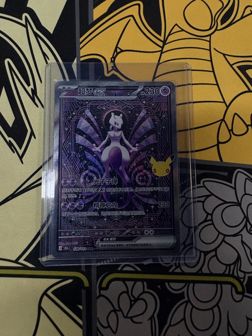 A Pokémon trading card, specifically a Mewtwo card (number 0230) in a protective sleeve, placed on top of other Pokémon-themed artwork including what appears to be Pikachu and another character.
