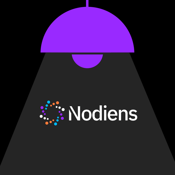 A purple lampshade illuminates the word 'Nodiens' next to a circular logo of colorful dots on a dark background.
