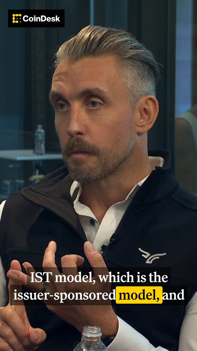 A man in a black vest and white collared shirt gestures with his hands while speaking, with a CoinDesk logo in the top-left corner and a subtitle reading "IST model, which is the issuer-sponsored model, and" overlaid at the bottom. The image appears to be a still from an interview with Chris Tyrer, President of Bullish Exchange, who discusses different tokenization models for stocks.