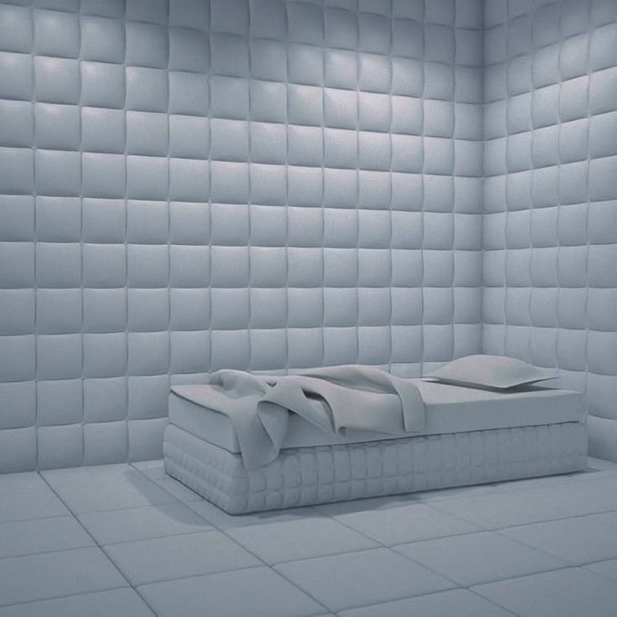 A minimalist pale blue padded room containing a low mattress on the floor. The sterile, soft-surfaced aesthetic mirrors the post's "locking in" vibe, suggesting a serene, undistracted mental space for focusing on $ANSEM.