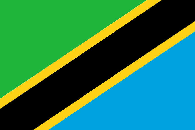 The image shows the flag of Tanzania, featuring a diagonal black stripe bordered by yellow that divides the green upper-left and blue lower-right sections. It accompanies news about Tanzania's central bank developing regulations for cryptocurrencies and stablecoins, visually representing the nation where these new financial policies are being implemented.