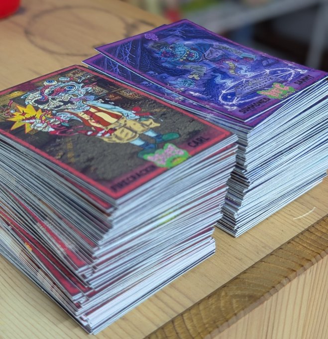Two large stacks of Pokémon trading cards, including what appears to be Charizard and other holographic cards, sitting on a wooden surface.
