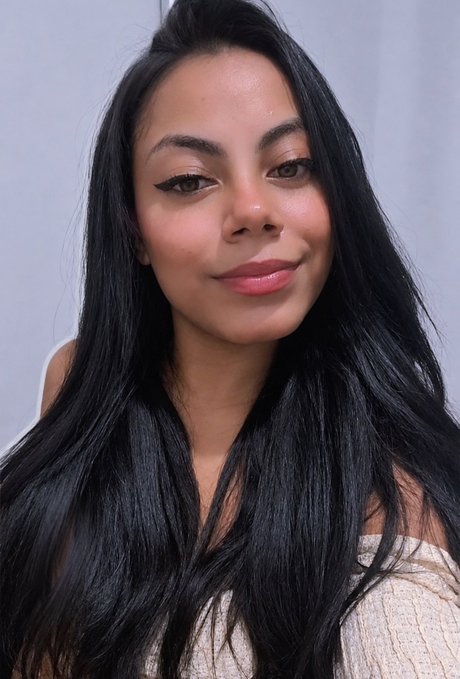 A close-up portrait shows a woman with long black hair, winged eyeliner, and glossy pink lips, smiling softly at the camera.