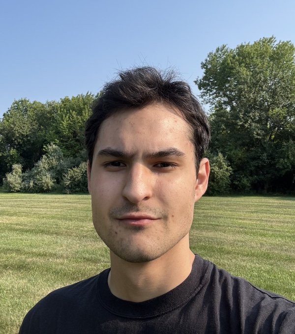 A young man smiles in a selfie taken in a grassy field with trees behind him, marking his 21st birthday as he reflects on a challenging yet rewarding year, with the caption emphasizing responsibility, perseverance, and a mention of Solana.