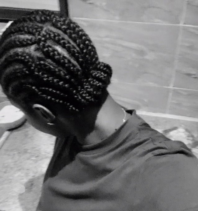 A person with their head tilted down, showcasing an intricate braided hairstyle featuring cornrows gathered into a low bun. The black-and-white photo highlights the detailed braiding pattern, complementing the post's question about the new hairstyle.