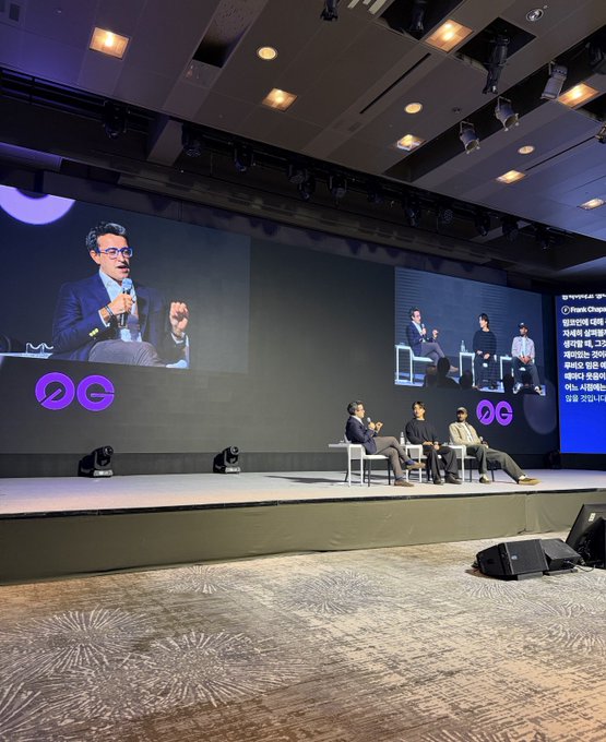 A panel discussion takes place on stage at a Korea Blockchain Week conference, with four speakers seated in chairs while a large screen displays a close-up of the speaker, alongside a presentation slide titled "Web3 Panel: Smart..." listing speakers from WEMIX, SK Square, BORA, and Playduce. The image captures the scale and international engagement of the event referenced in the post about Korea's growing crypto market and efforts to attract foreign capital.