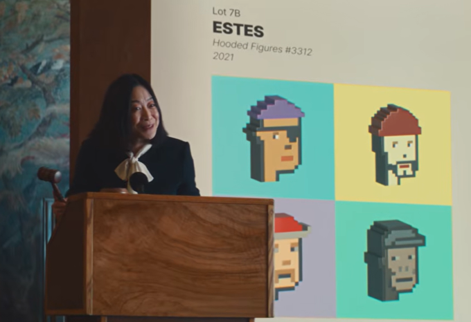 A woman speaking at a wooden podium during an auction, standing in front of a screen displaying Lot 7B 'ESTES Hooded Figures #3312' 2021, which features four pixel-art character portraits.