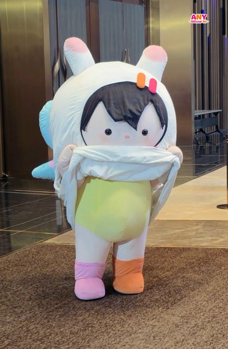 A person poses in a cute mascot costume featuring pink rabbit ears, a yellow body, and oversized pastel shoes, lifting the hood to reveal a cartoonish face. The "ANY" logo appears in the upper right corner, tying the image to the #ANY and #MoonshadowSeriesFinalEP hashtags from the caption.