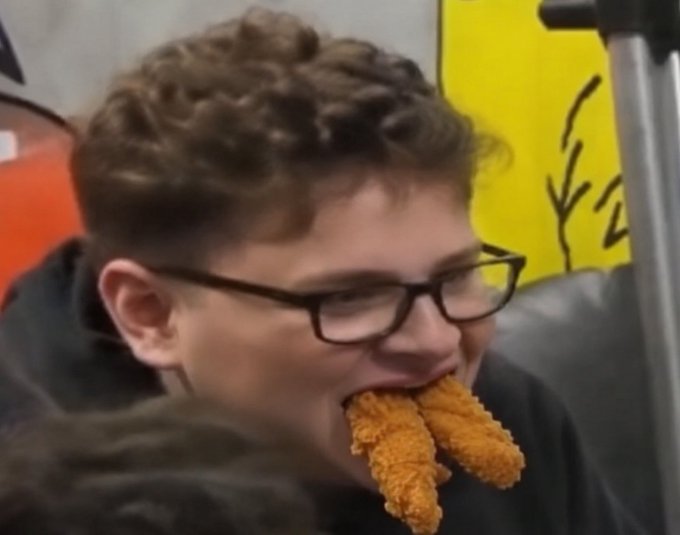 A young man with glasses enthusiastically bites into a cluster of fried chicken tenders, humorously embodying the "$tendies" meme referenced in the post, which jokes about crypto tokens named after the beloved food and their potential to reach massive market caps.