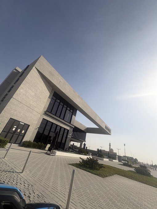 A modern building with a cantilevered roof and the word "HERO" displayed prominently on the facade, photographed on a bright, sunny day with a clear paved area in the foreground. The image relates to the post "GM GM GM" by showcasing a sleek, contemporary architecture that could symbolize "Grand Moments" or serve as a visual representation of a notable location.