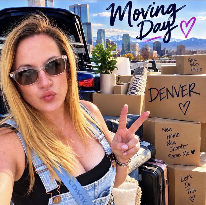 A woman in denim overalls and sunglasses takes a selfie making a peace sign in front of a car loaded with moving boxes, including ones labeled "DENVER," "Good Vibes Only," "New Home New Chapter Same Me," and "Let's Do This," with the Denver skyline and mountains in the background. The handwritten "Moving Day" text at the top and her pouty expression capture her reluctant but excited start to a new chapter—matching her post about hating the moving process while embracing the fresh beginning ahead.