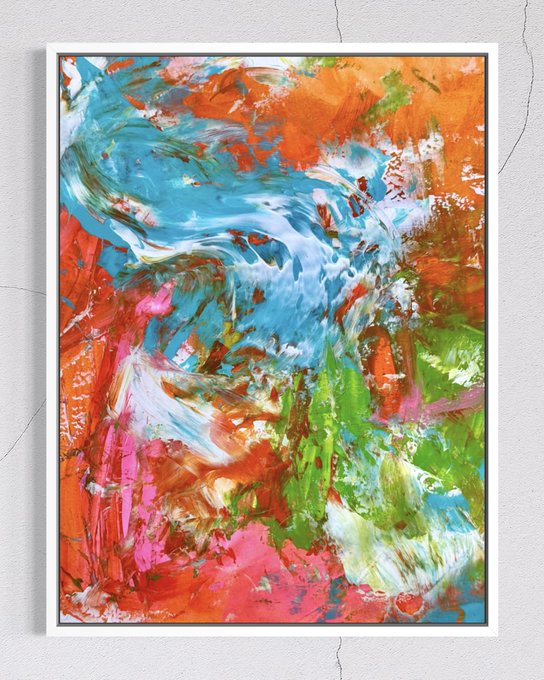 An abstract painting in a white frame mounted on a textured wall, featuring vibrant splashes of orange, blue, green, pink, and red colors in an expressive, chaotic composition.