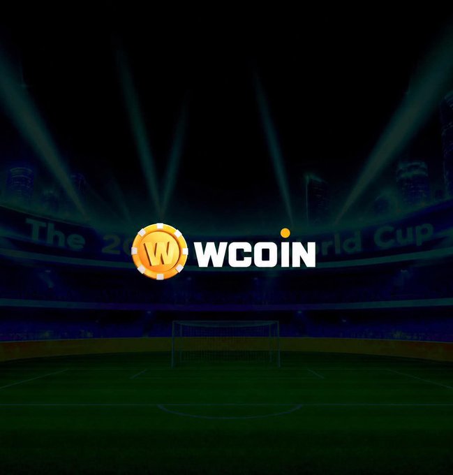 WCOIN logo (gold coin with 'W') displayed over a dark soccer stadium at night with stadium lights and 'The World Cup' faintly visible on banners.