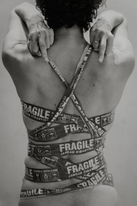 A person's back is wrapped in tape labeled "FRAGILE" and "HANDLE WITH CARE," reflecting the theme "Fuck cancer (Who said fragile II)" minted by @mariafynsknorup.