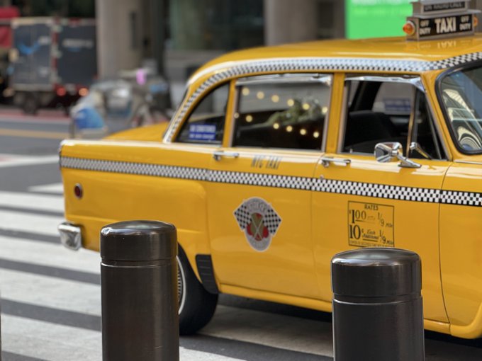 A classic yellow taxi cab on a city street with visible text 'TAXI OFF DUTY' and rate information on the door.