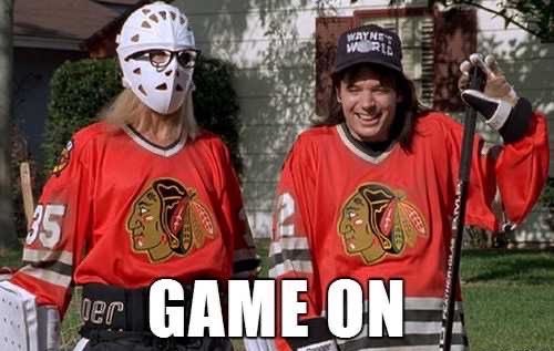 A meme-style image of two people wearing Chicago Blackhawks jerseys and hockey masks holding hockey sticks outdoors, with text 'GAME ON' overlaid.