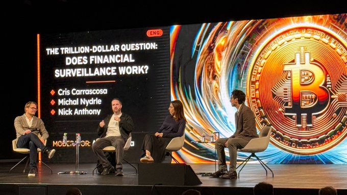 Panel discussion titled 'THE TRILLION-DOLLAR QUESTION: DOES FINANCIAL SURVEILLANCE WORK?' featuring speakers Cris Carrascosa, Michal Nydrle, and Nick Anthony on stage with a large Bitcoin graphic.