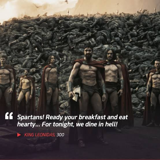 A movie still from '300' showing King Leonidas and Spartan warriors standing before a massive pile of enemy bodies, with the quote: 'Spartans! Ready your breakfast and eat hearty... For tonight, we dine in hell!!' attributed to King Leonidas.