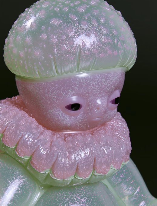 A glossy, glittery pink and green figurine with a ruffled collar and vacant black eyes stares blankly against a black background, its empty, hollow expression perfectly mirroring the post's joke about a deflated wallet crying over hundreds of worthless NFTs.