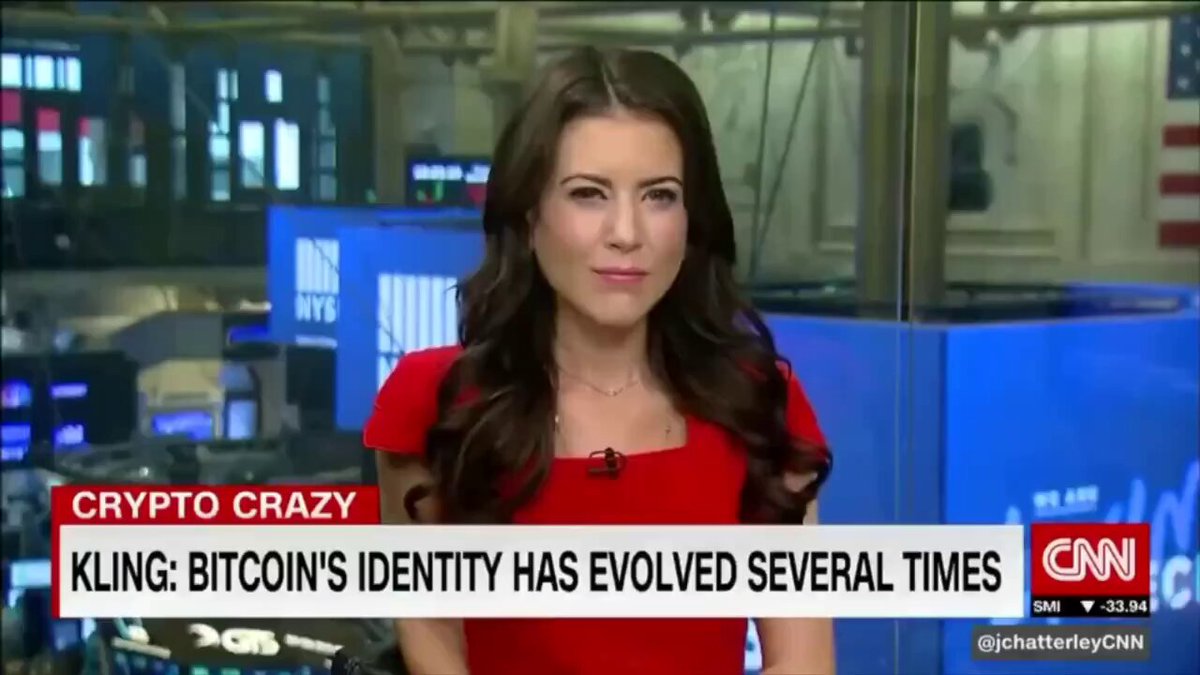 The image features a woman wearing a red dress, standing in front of a blue background with a news anchor reporting about Bitcoin's identity. The text "Kling: Bitcoin's identity has evolved several times" can be seen in the image.