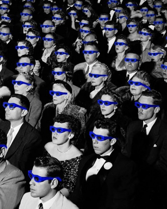 A black and white photograph of a vintage movie theater audience, with every person wearing digitally added blue 3D glasses.