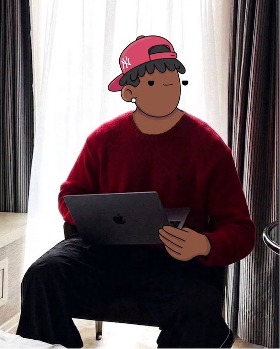 A person wearing a red sweater and a pink NY Yankees cap sits by a window working on a MacBook, with their face covered by a cartoon sticker.
