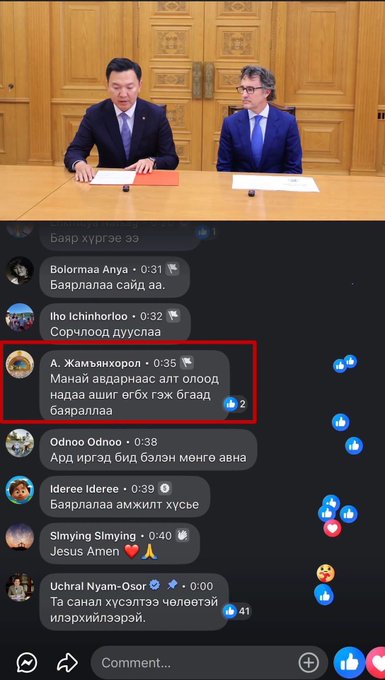A Facebook livestream screenshot showing two men in suits at a desk (one Asian, one Western with glasses), with live chat comments in Mongolian, including a highlighted comment from 'А. Жамьяндорж' receiving 2 likes.