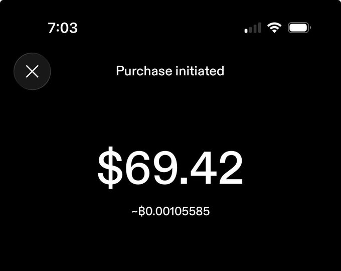 A mobile app screenshot on a black background showing 'Purchase initiated' for $69.42 (approximately Ƀ0.00105585 Bitcoin), with the time 7:03 at the top.