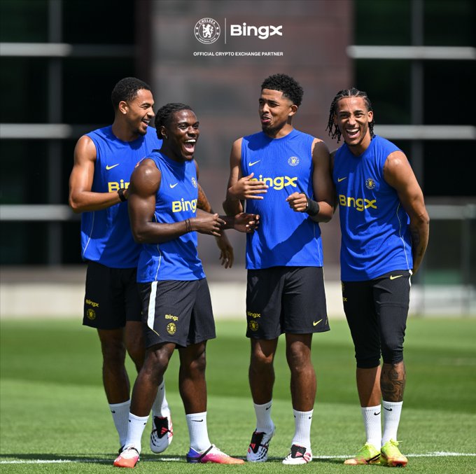 Four Chelsea FC players share a laugh during a training session, with the BingX logo and "Official Crypto Exchange Partner" branding visible on their blue training kits and at the top of the image. The lighthearted moment captures the camaraderie between teammates, fitting the playful "POV: Watching your friend panic sell" caption and BingX's #TrainedOnGreatness campaign.