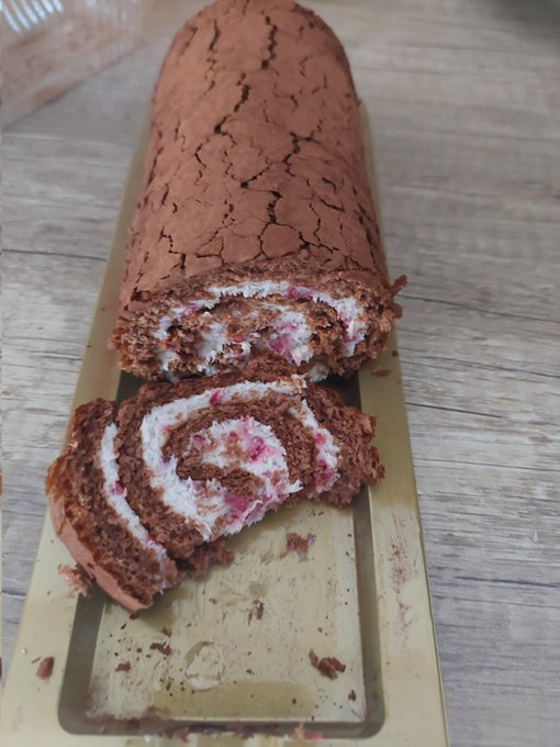 The image features a chocolate cake with pink frosting, cut into slices and placed on a tray or plate. The cake has been sliced into two pieces, one of which has a bite taken out of it. The background appears to be a wooden surface, possibly a table or countertop. The post includes the text "Lets try perps rocket on @defiapp Let's back to $HOME We are building HOME together Enjoy". This suggests that the image is related to a social media post promoting a dessert called "perps rocket" and encourages people to share their experiences with it, possibly including pictures of the dessert.