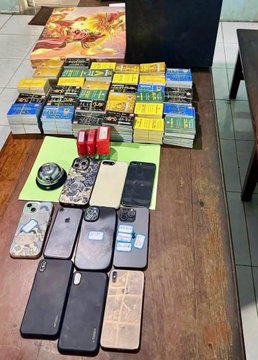 A display of multiple smartphones, boxes, phone cases, and accessories arranged on a green mat on the floor.