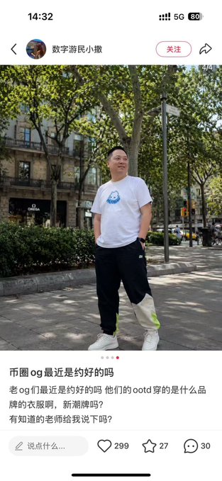 The image shows a man standing outside, posing for a photo with his phone. The photo has been posted on social media, as indicated by the caption "哪里搞得衣服?还是 #HUOBAO 这是新上的周边吗？挺潮的 如何得到啊?". The man is wearing a white shirt and black pants, with his hands in his pockets.