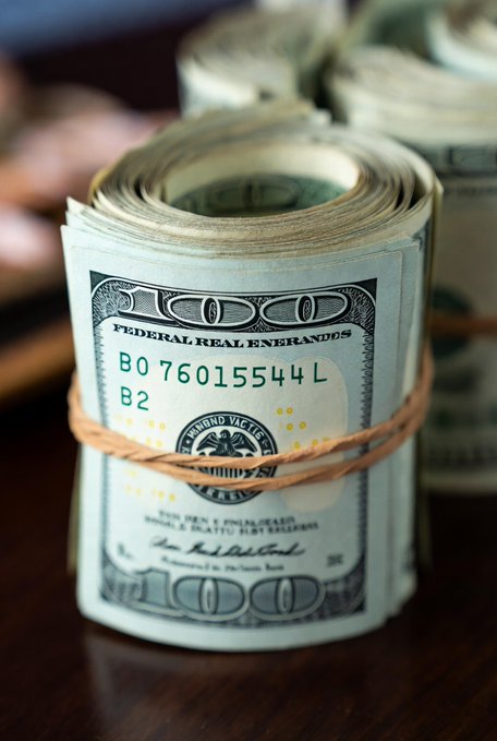 The image features a stack of US dollar bills tied together with a brown string, sitting on top of a wooden surface. The text "HUGE" is visible in the image, which could be related to the Blockchain or tokenised fiat concept. The post also mentions that tokenisation can make global payments faster and safer, potentially reducing transaction costs and increasing the speed at which transactions are completed.