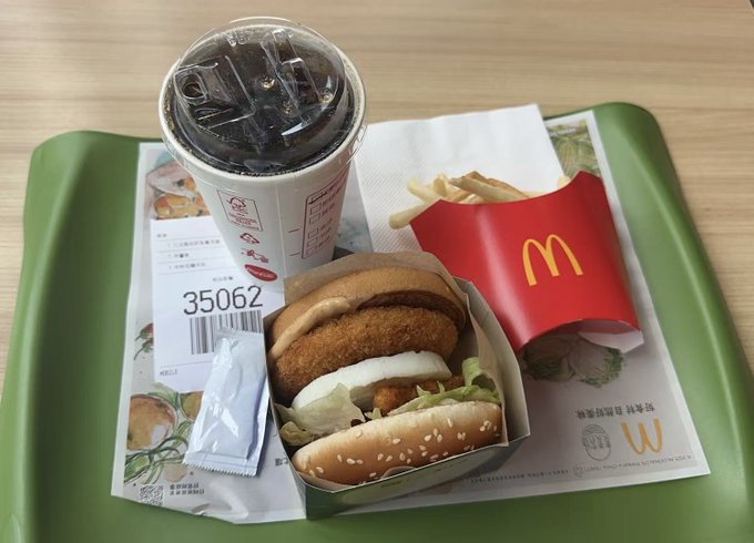 A green McDonald's tray holds a dark-colored drink, a crispy chicken sandwich, a small carton of fries, and a receipt numbered '35062'.
