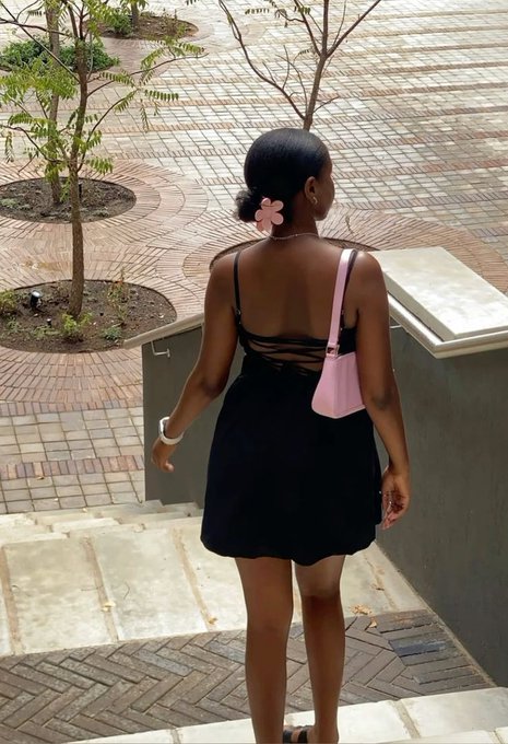 The image features a woman wearing a black dress with a pink purse slung over her shoulder as she walks down a brick walkway or staircase. The photo has been edited to include text that reads "blissful morning it's the second day of the new month, please remember why you started i have a post on my pinned please check it out". This suggests that the woman is enjoying herself and wants others to know about her positive experience in the new month.

The image also includes a potted plant near the top left corner, which adds some greenery to the scene. The overall composition of the photo seems to be focused on the woman's outfit and accessories while conveying a sense of joy or contentment.