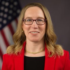 A professional headshot shows a woman with shoulder-length blonde hair, wearing glasses, a red blazer over a black top, and a gold chain necklace, standing in front of an American flag—likely an official government portrait that ties into the post's discussion of federal agencies like the SEC and CFTC developing understanding of zero knowledge proofs and decentralized exchange platforms like Hyperliquid and Lighter.