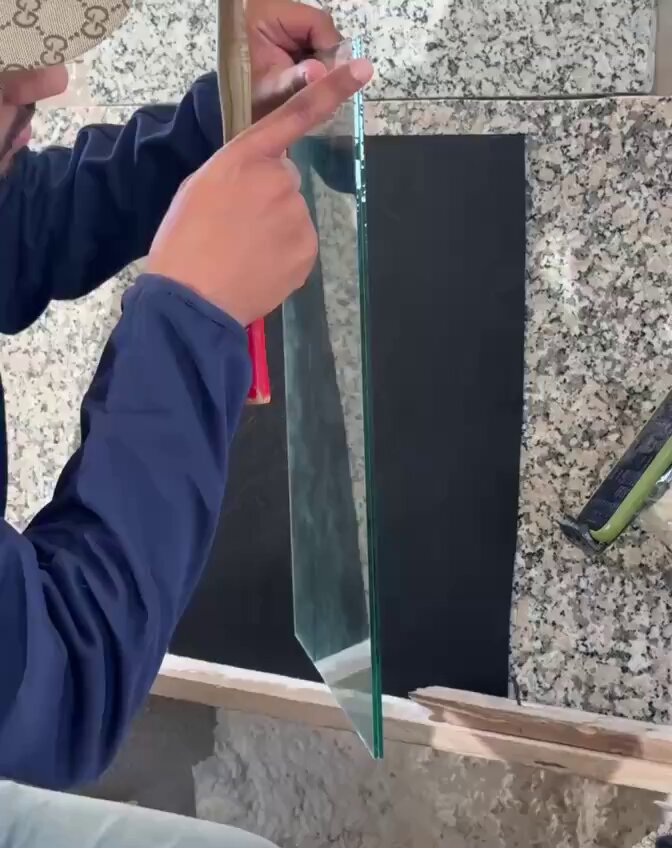 The image features a person wearing a blue jacket holding up a glass window pane with their left hand while pointing at it with their right hand, possibly discussing or explaining something about the glass. The background of the image shows a stone wall, which could be part of a building or an art installation. The post in question is about a project called @ZelijOrigins, which is a collection of generative Zellige pieces by a Moroccan artist named @ZelijOrigins.