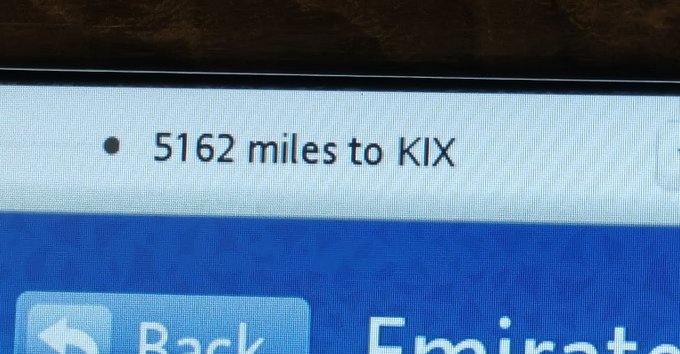 A close-up of an Emirates airline in-flight entertainment screen displaying '5162 miles to KIX' (likely Osaka Kansai International Airport), with navigation options 'Back' visible below.