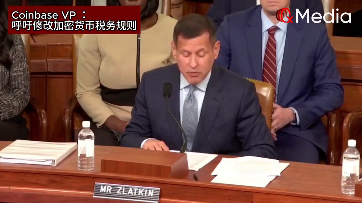 The image shows a man sitting at a desk, wearing a suit and tie, with papers and water bottles nearby. The scene appears to be set in a courtroom or a formal setting where the man is likely participating as an expert witness. The text on the image reads "Coinbase MVD i", which could potentially be related to the case being discussed, but it's unclear from the image alone what that means.