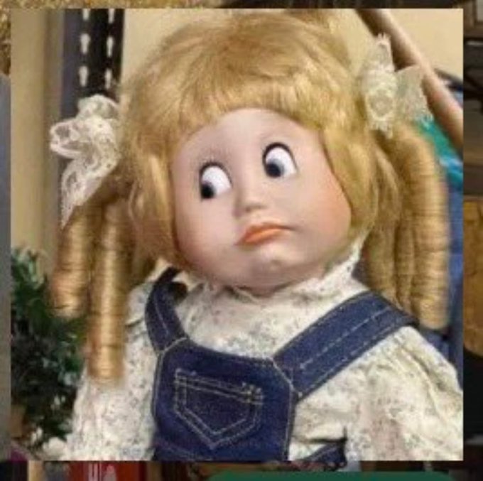 A porcelain doll with curly blonde hair, crossed eyes, and a denim overalls outfit is featured in the image, creating a humorous and slightly unsettling visual. The doll's quirky, wide-eyed expression pairs with the tweet "If you see this tweet, it means you have monad card," suggesting a playful, surreal internet culture reference where seeing the strange doll signifies receiving a "monad card."