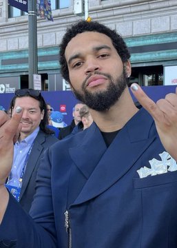 Chicago Bears quarterback Caleb Williams shows off his freshly trimmed mustache and new hairstyle while posing with peace signs on what appears to be a red carpet event. The trendy new look aligns with the post's mention of his "brand new look," suggesting a recent style transformation for the NFL star.
