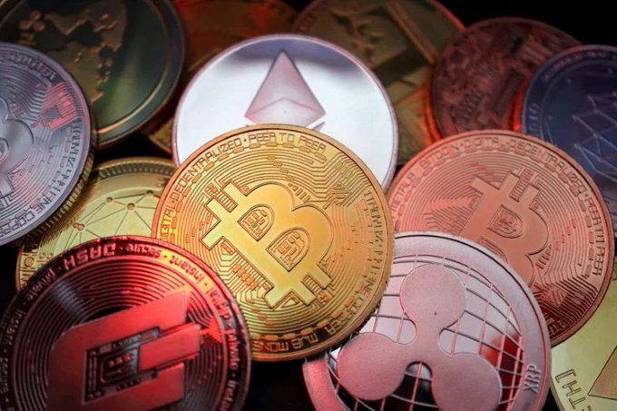 A close-up of various physical cryptocurrency coins including Bitcoin, Ethereum, and Ripple XRP piled together.