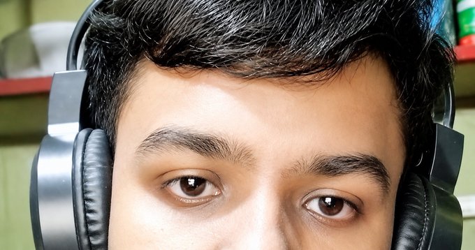 Close-up selfie of a man wearing large black over-ear headphones, with only his eyes, eyebrows, and forehead visible in the frame.