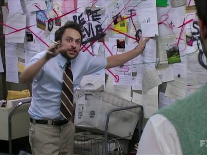 A man in a light blue shirt and tie stands in front of a conspiracy board covered in papers and red string, pointing animatedly with a marker in his hand.