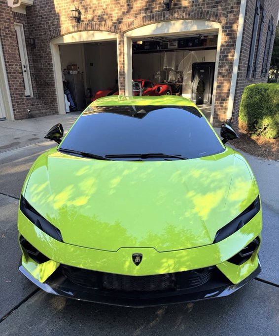 A bright lime-green Lamborghini with black accents is parked in front of a brick house with open garages, matching the post’s giveaway theme of “1 AntHood = 1 Lambo” and “Free mint.” No clear additional text or numbers are visible beyond the Lamborghini badge.